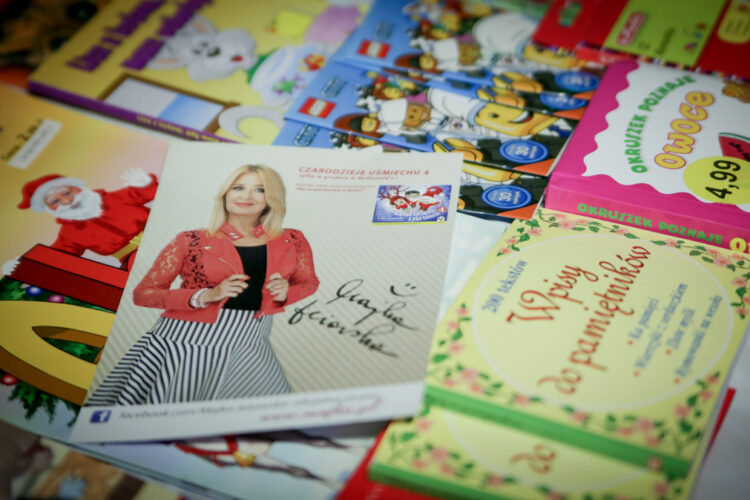 zdjęcie Majki Jeżowskiej z autografem, w tle książki